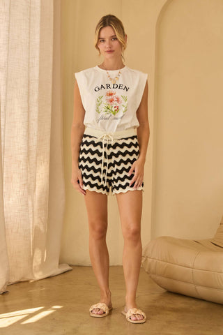 Woman wearing black and cream zig zag striped knit shorts with scalloped hem styled with a sleeveless graphic top.