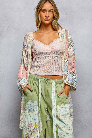 Woman wearing Vintage Bloom Patchwork Cardigan with pastel granny-square crochet and draped silhouette.