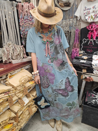 Woman wearing blue butterfly floral collage t-shirt dress styled with western hat and layered jewelry.
