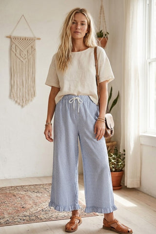 Woman wearing checkered gingham fully lined wide leg pants with drawstring waist and ruffle hem detail