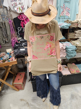 Woman wearing Pink Is My Signature Color graphic tattered shirt styled with hat and boutique accessories.
