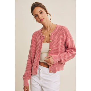 Woman wearing mineral-washed pink cable knit cardigan with button-front detail.