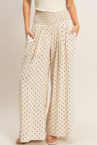 Woman wearing neutral polka dot wide-leg pants with elastic waistband and side pockets.